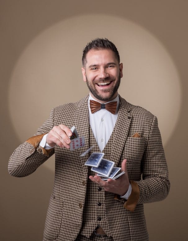 Le magicien mentaliste Pierrick Martinet manipule les cartes, les faisant passer d'une main à l'autre, avec un grand sourire.